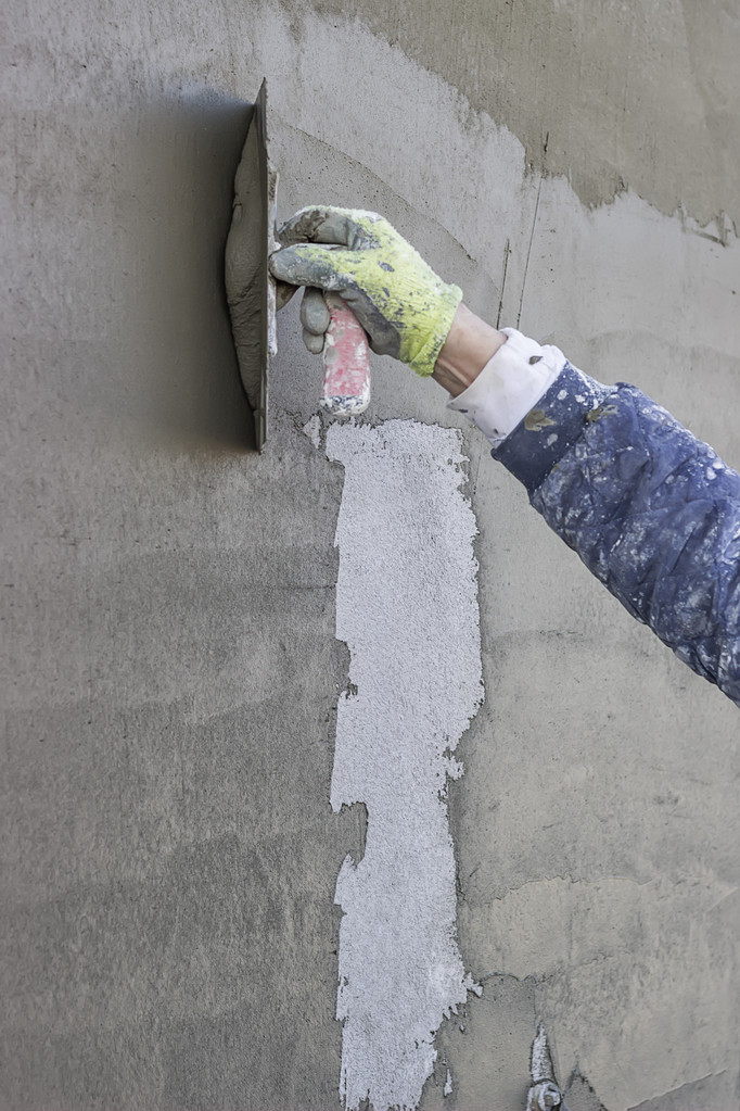 Workers hand plastering an exterior wall